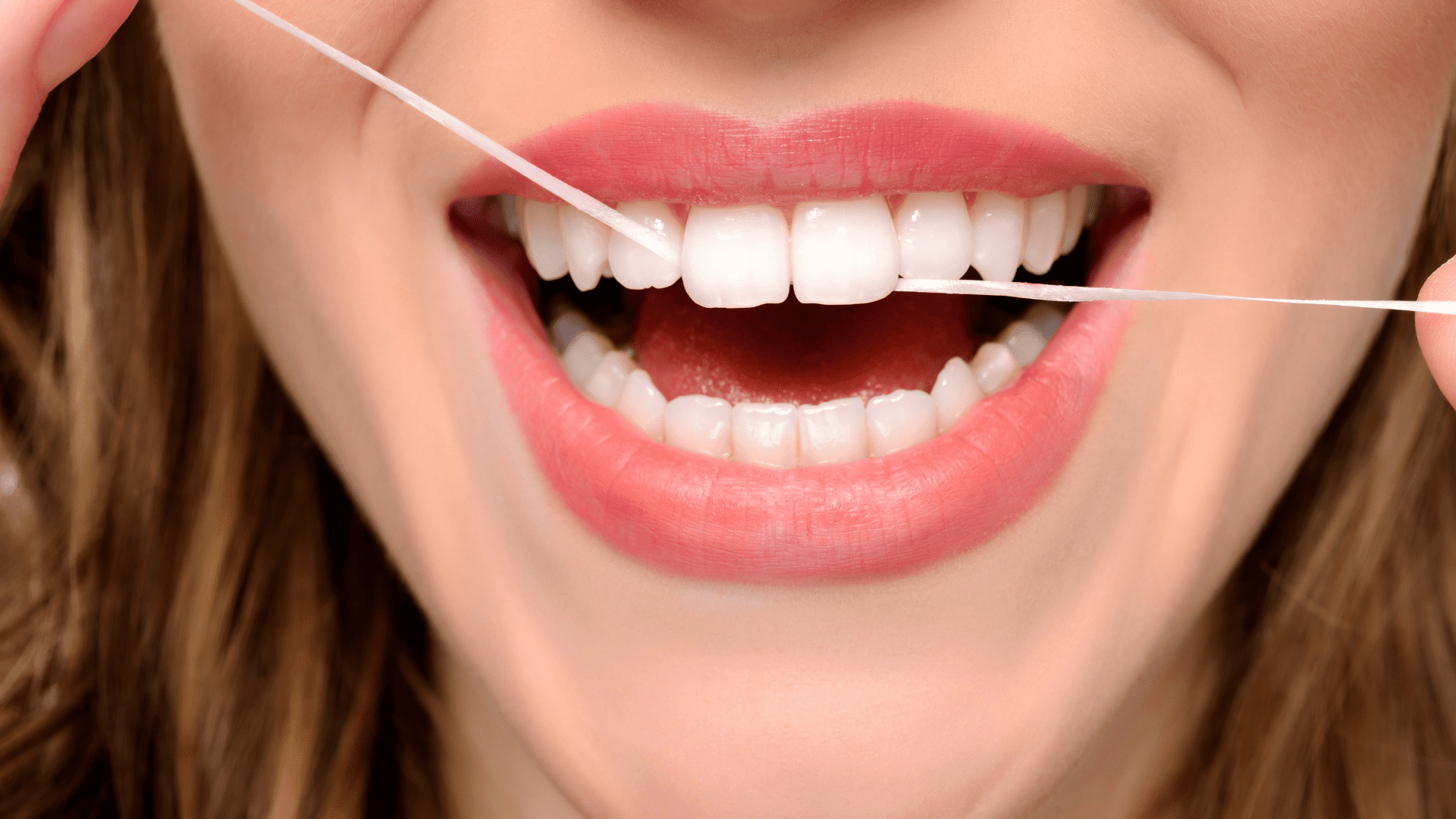 Woman flossing newly cleaned teeth by a Nashville dental cleaning professional